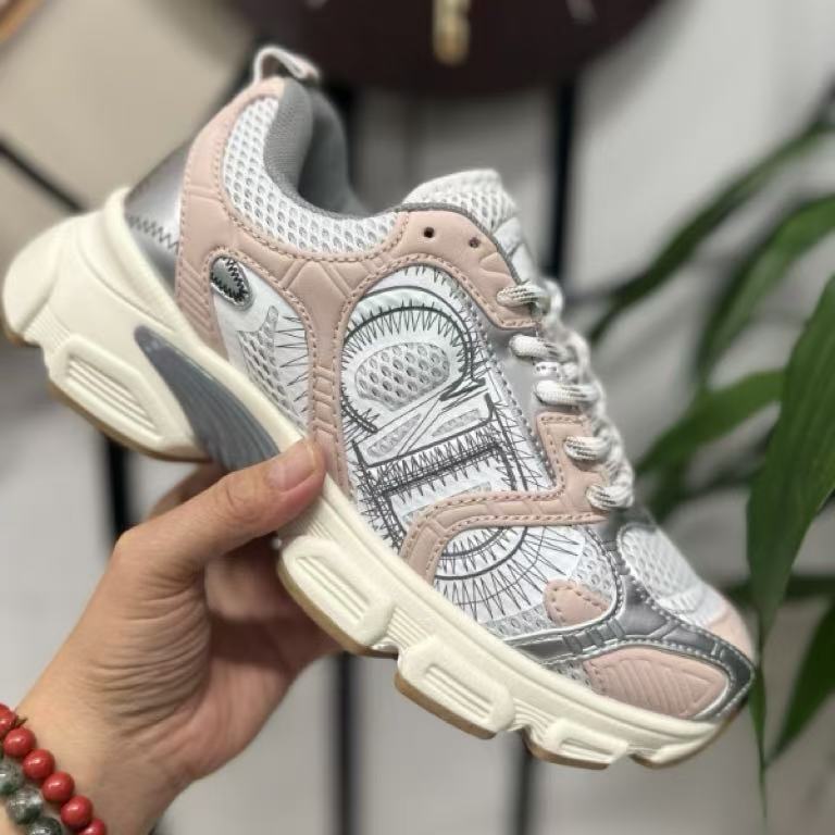 Pink and gray sneaker held by a hand with a blurred background