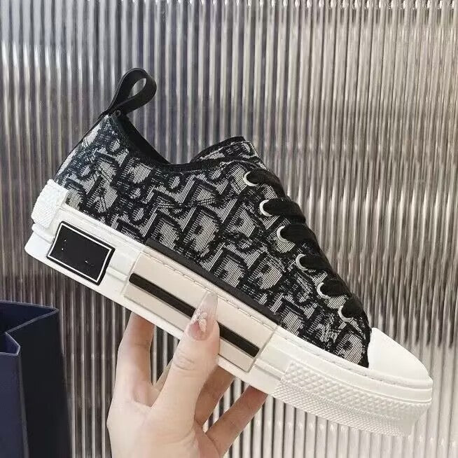 Black and white sneaker with a pattern held by a hand against a metallic background