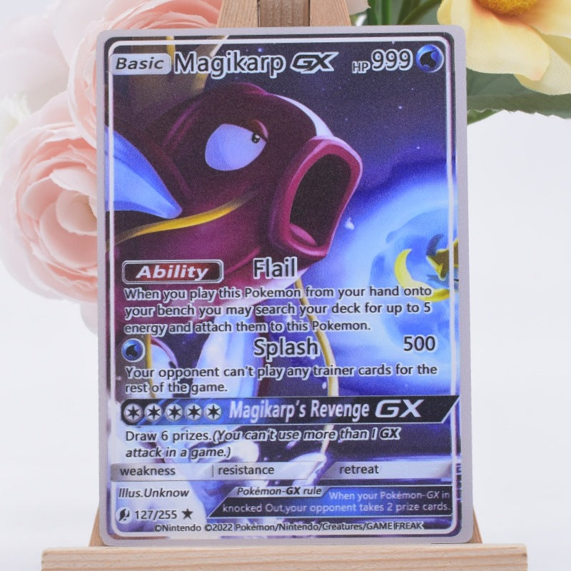 A Magic: The Gathering trading card of Magikarp GX (base version) displayed on a small wooden easel. The card features artwork of a purple and blue Magikarp with the text 'Basic' and 'Magikarp GX' at the top, set against a soft-focus background of pink roses and yellow flowers.