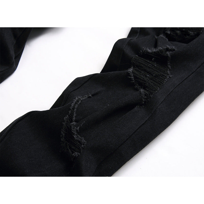 Close-up of black distressed jeans showing frayed ripped details on a white background.
