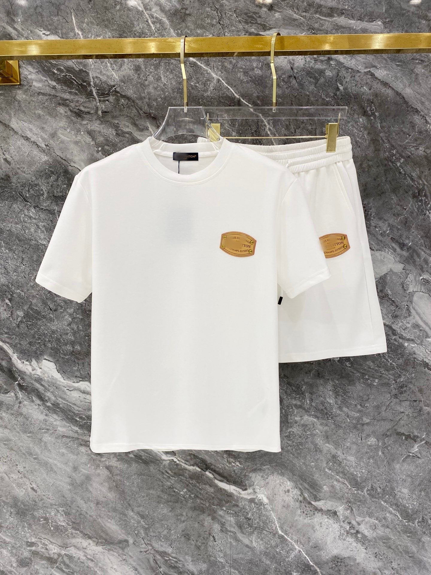White t-shirt and shorts set with gold accents on a marble background