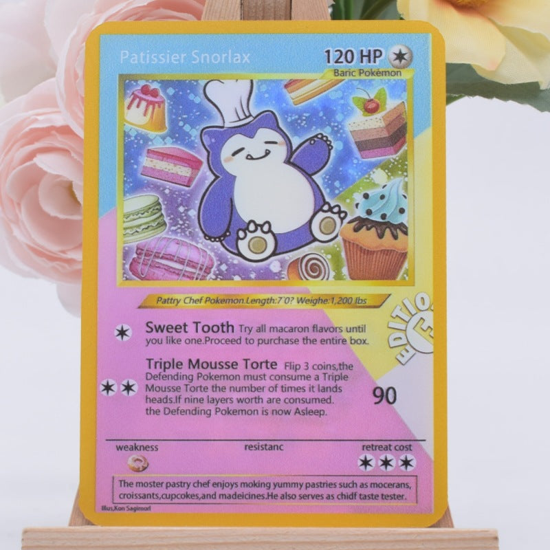 A Pokémon trading card featuring Patissier Snorlax, displayed upright on a small wooden stand with pink flowers blurred in the background.
