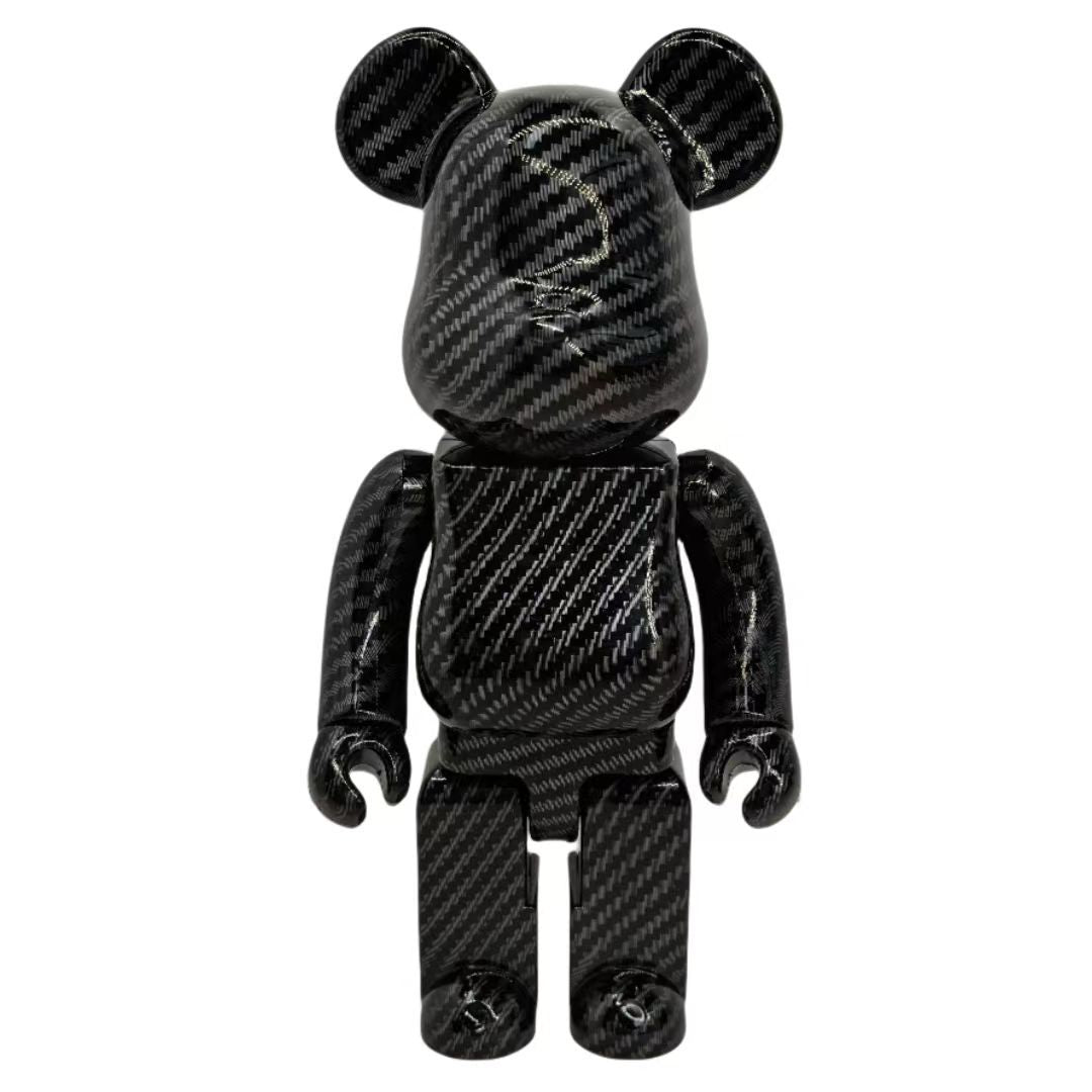 A black carbon fiber patterned bear figure toy, resembling a Bearbrick, shown from the front against a plain white background.