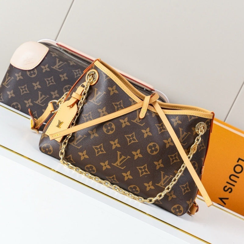 Louis Vuitton monogram canvas shoulder bag with tan leather trim and a gold chain strap, shown on a white surface with an orange Louis Vuitton box in the background.