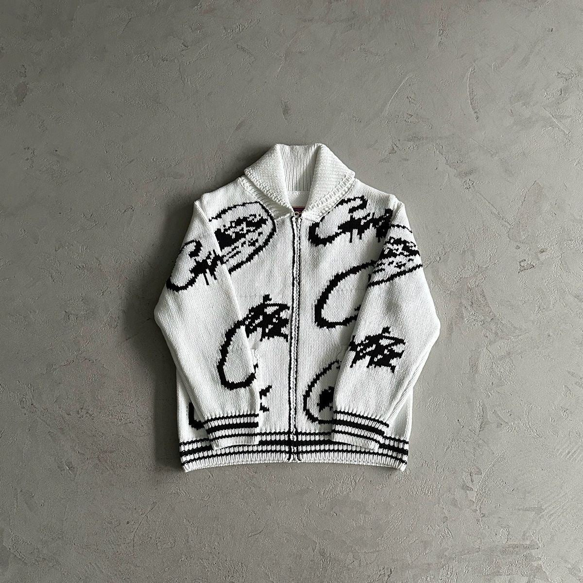 White sweater with black abstract patterns on a gray background
