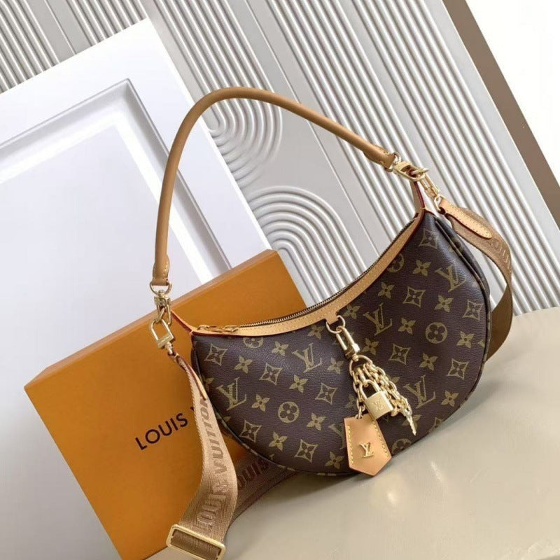 Louis Vuitton monogram canvas crescent shoulder bag with tan leather trim and strap, shown with an orange Louis Vuitton box on a light beige surface.