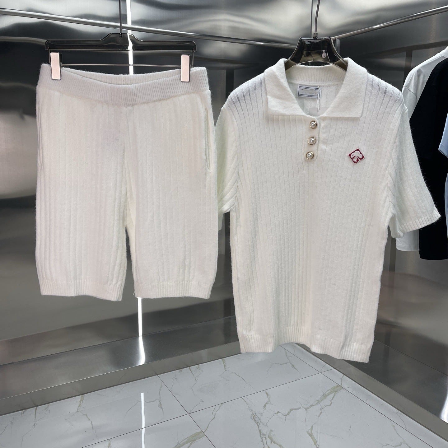 White ribbed polo shirt and shorts set hanging on a rack.
