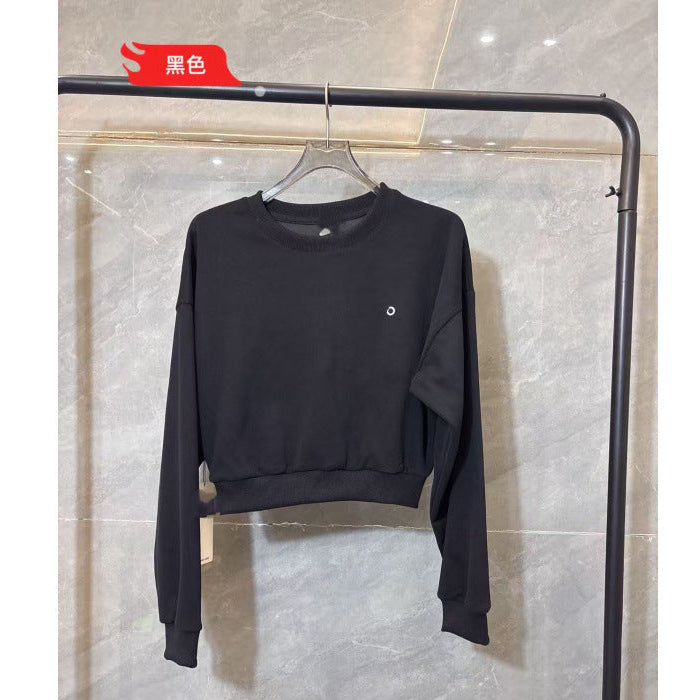 Black long-sleeve shirt on a hanger against a tiled wall.