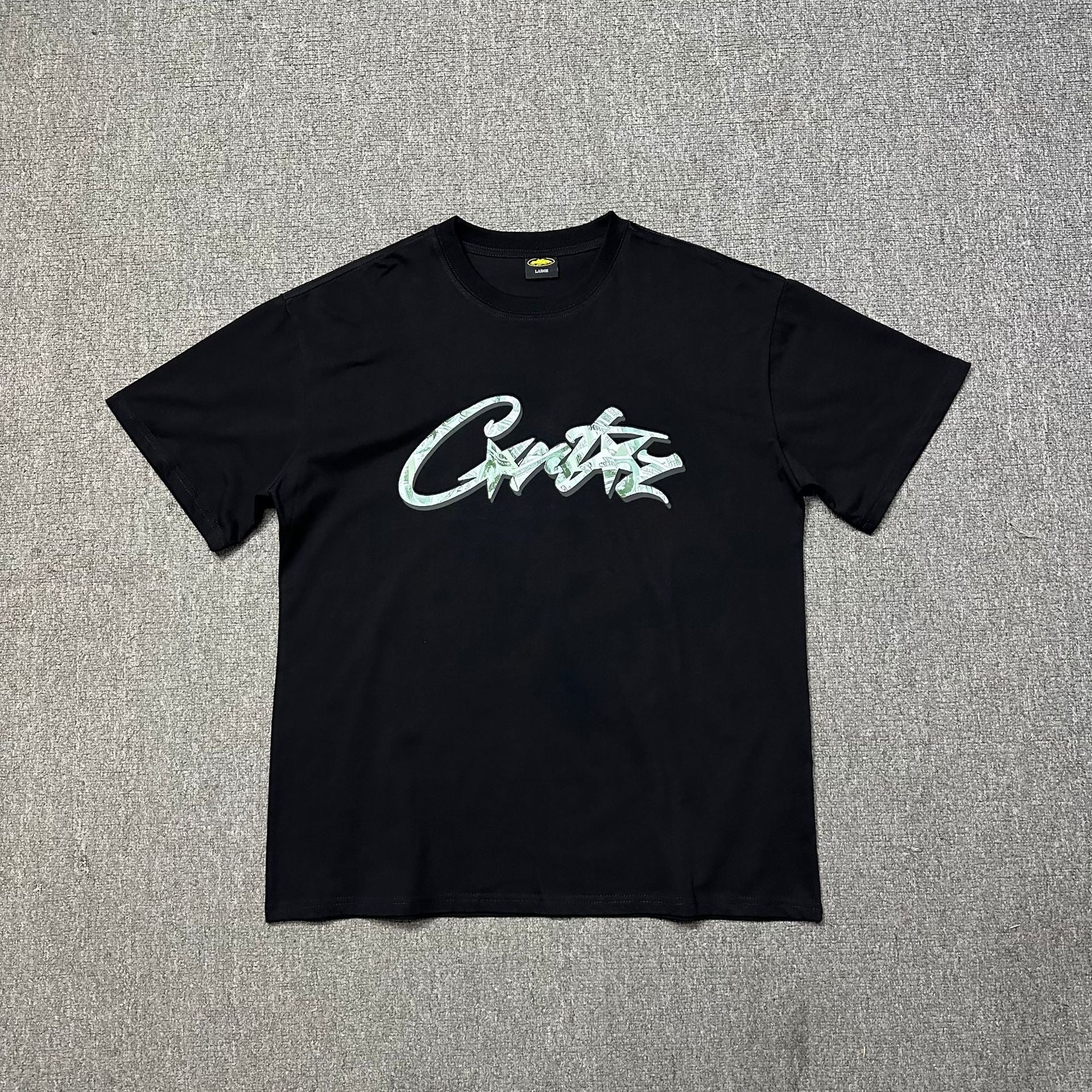 Black t-shirt with a logo on a gray textured background