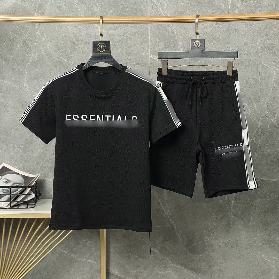 Black 'ESSENTIALS' t-shirt and shorts set on hangers against a gray background