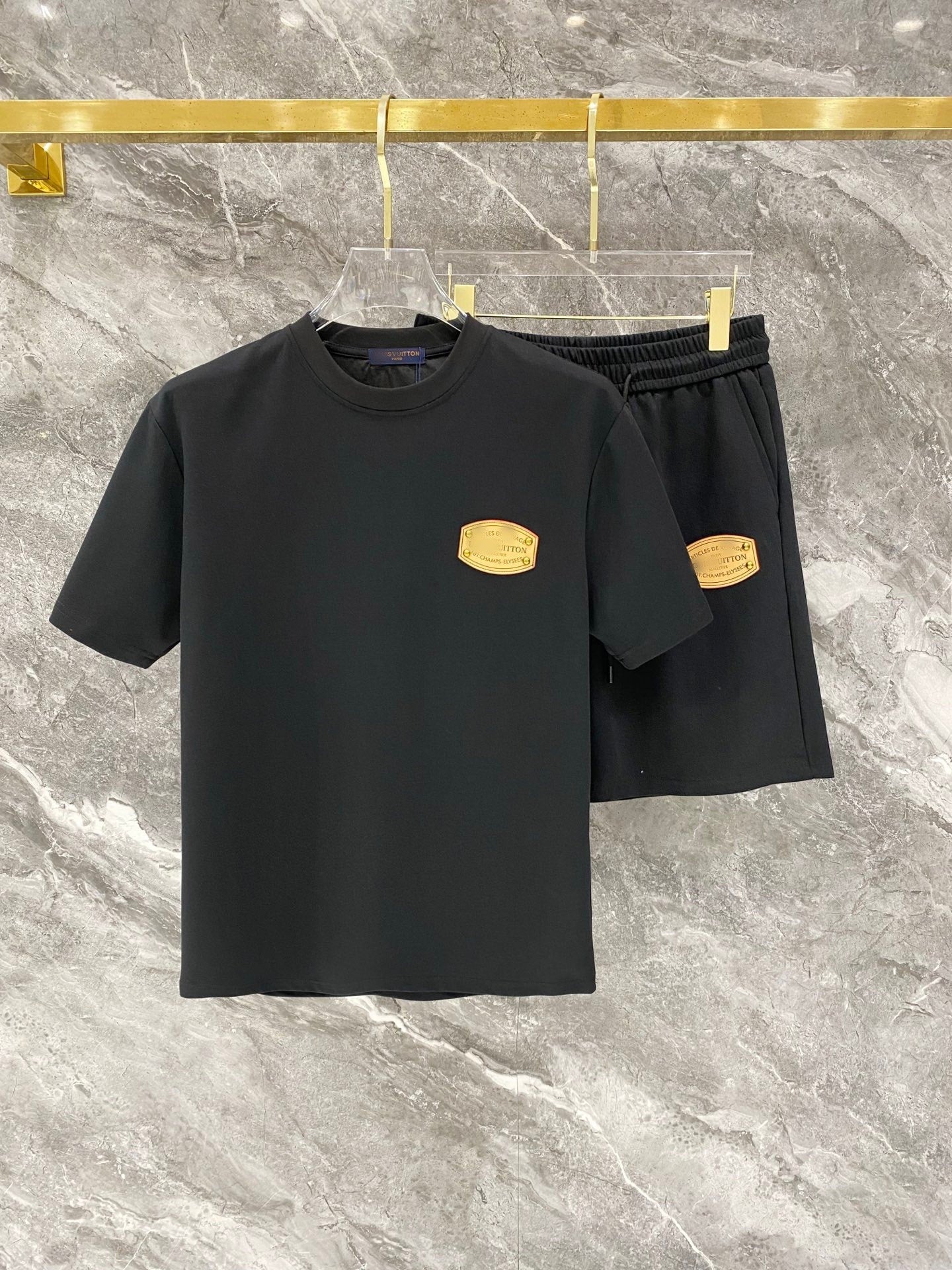 Black t-shirt and shorts set with gold logos on a marble surface