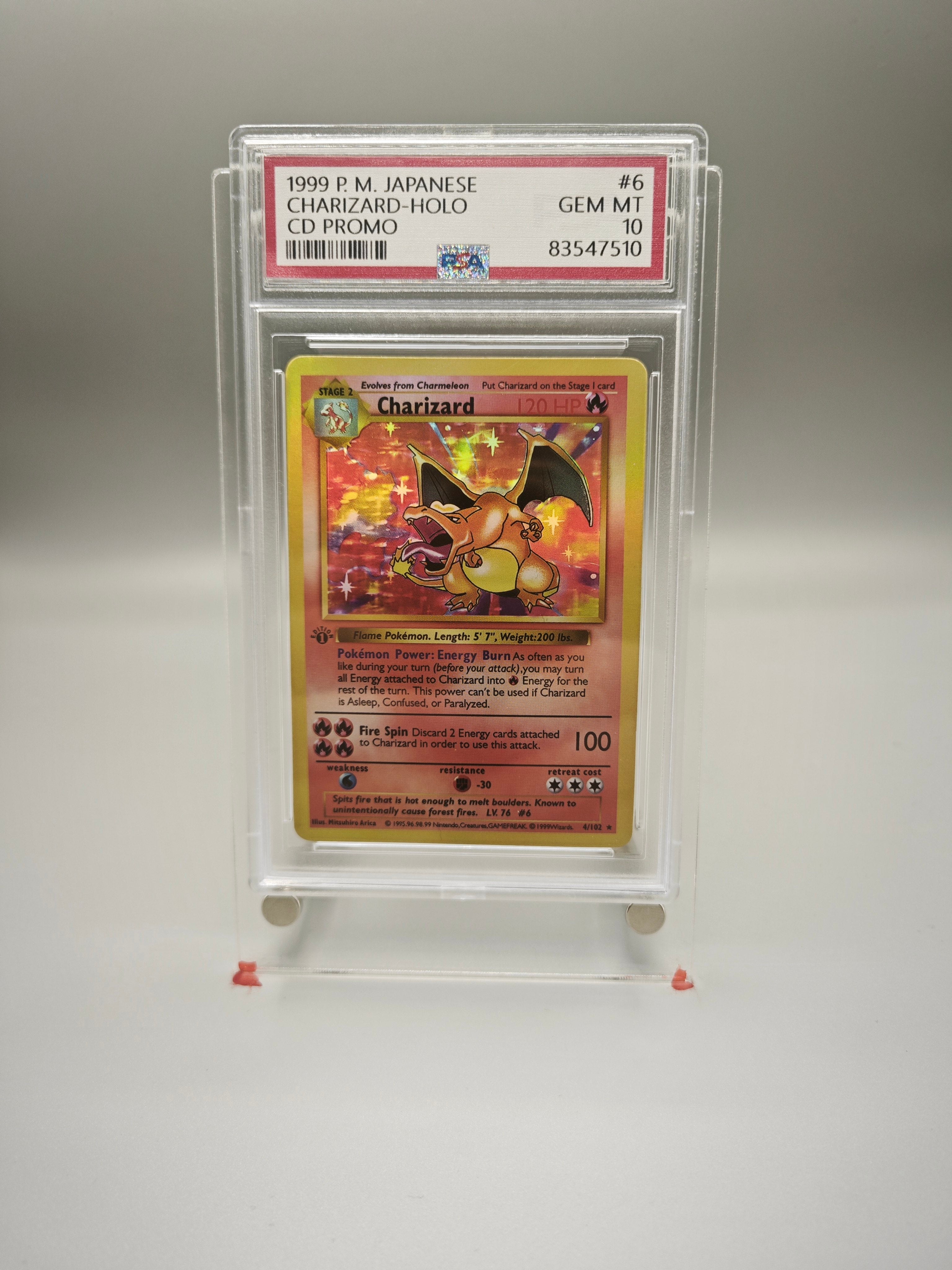 A graded 1999 Charizard holographic CD promo card in a clear PSA-style holder, photographed against a neutral gray background.