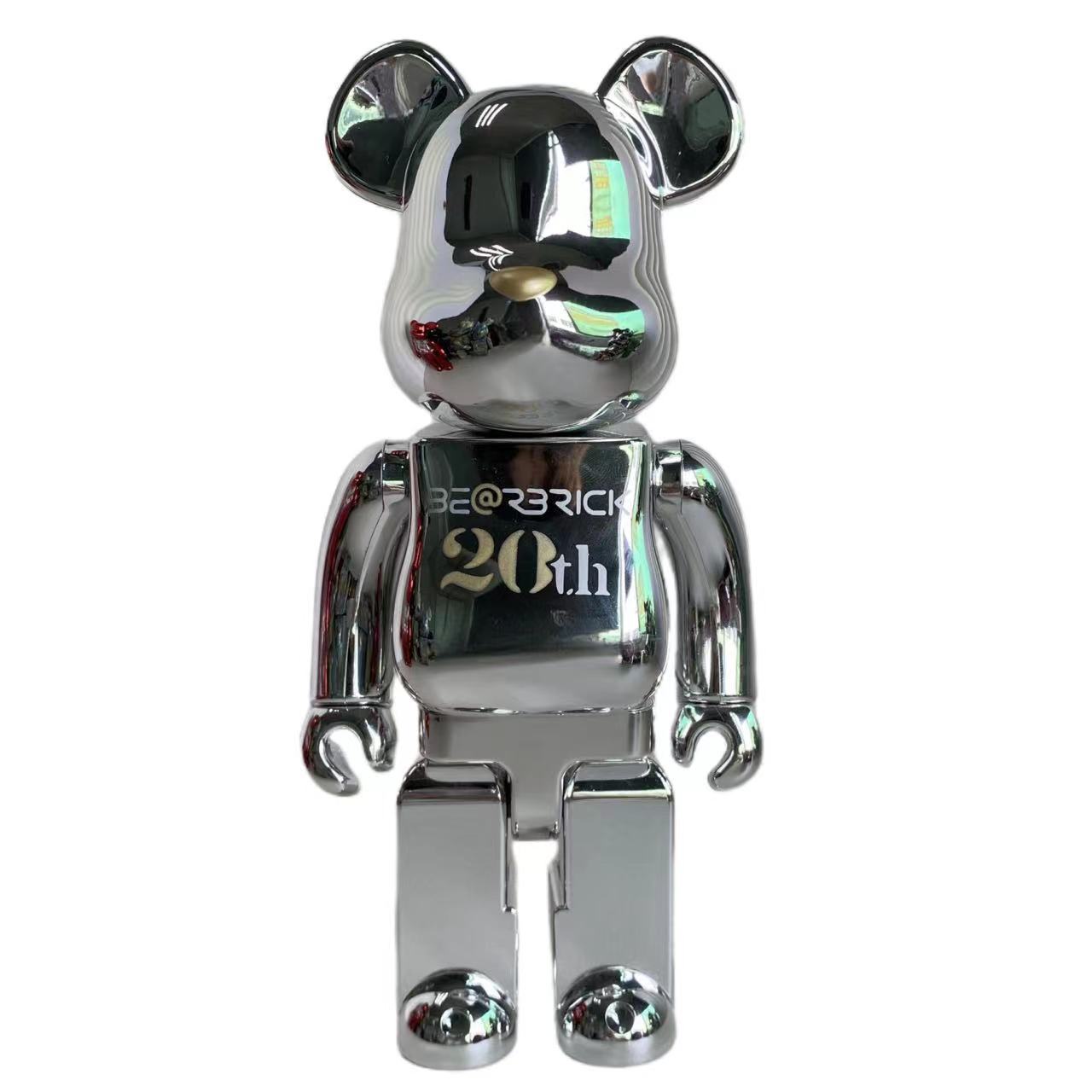 A metallic silver bear-shaped collectible figure with reflective chrome-like surfaces, standing against a plain white background. The chest area shows the text 'BE@RICK 20th' in gold and white lettering.