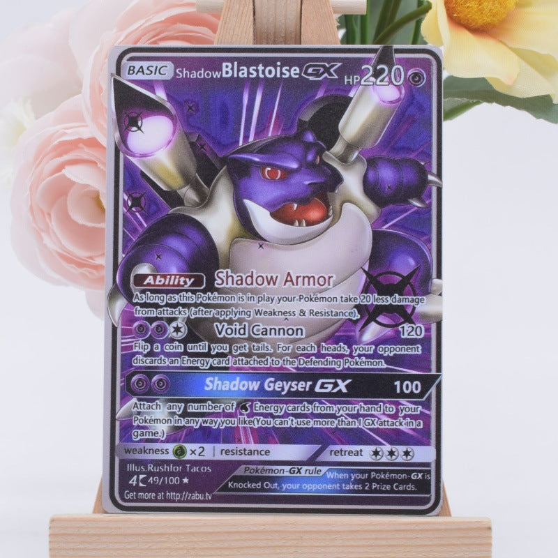 A Pokémon trading card featuring ShadowBlastoise GX, displayed upright on a small wooden stand with soft pink flowers and a yellow flower blurred in the background.