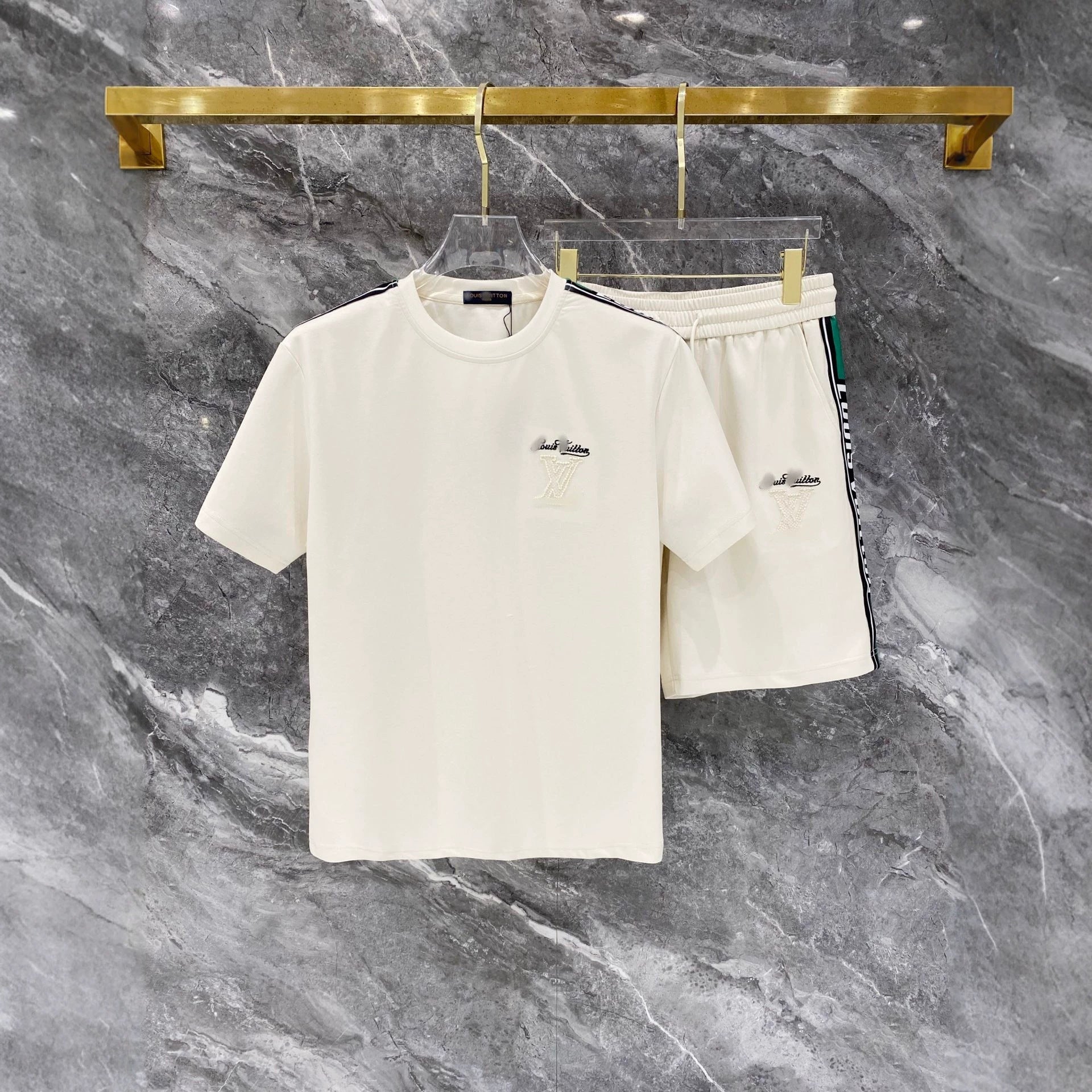 White t-shirt and shorts set on a hanger against a gray marble background