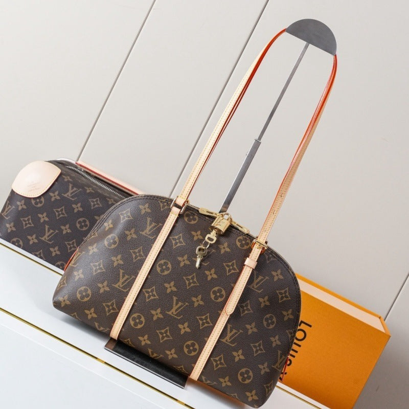 Louis Vuitton monogram canvas duffel bag with a structured dome shape, tan leather shoulder strap, and gold-tone hardware, displayed on a stand with a matching orange Louis Vuitton box in the background.
