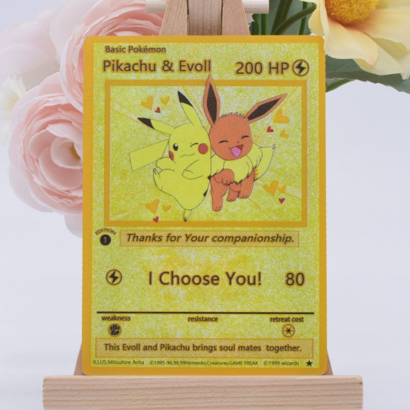 A holographic Pokémon trading card featuring Pikachu and Evoll, displayed on a small wooden stand with pink and yellow flowers in the background.