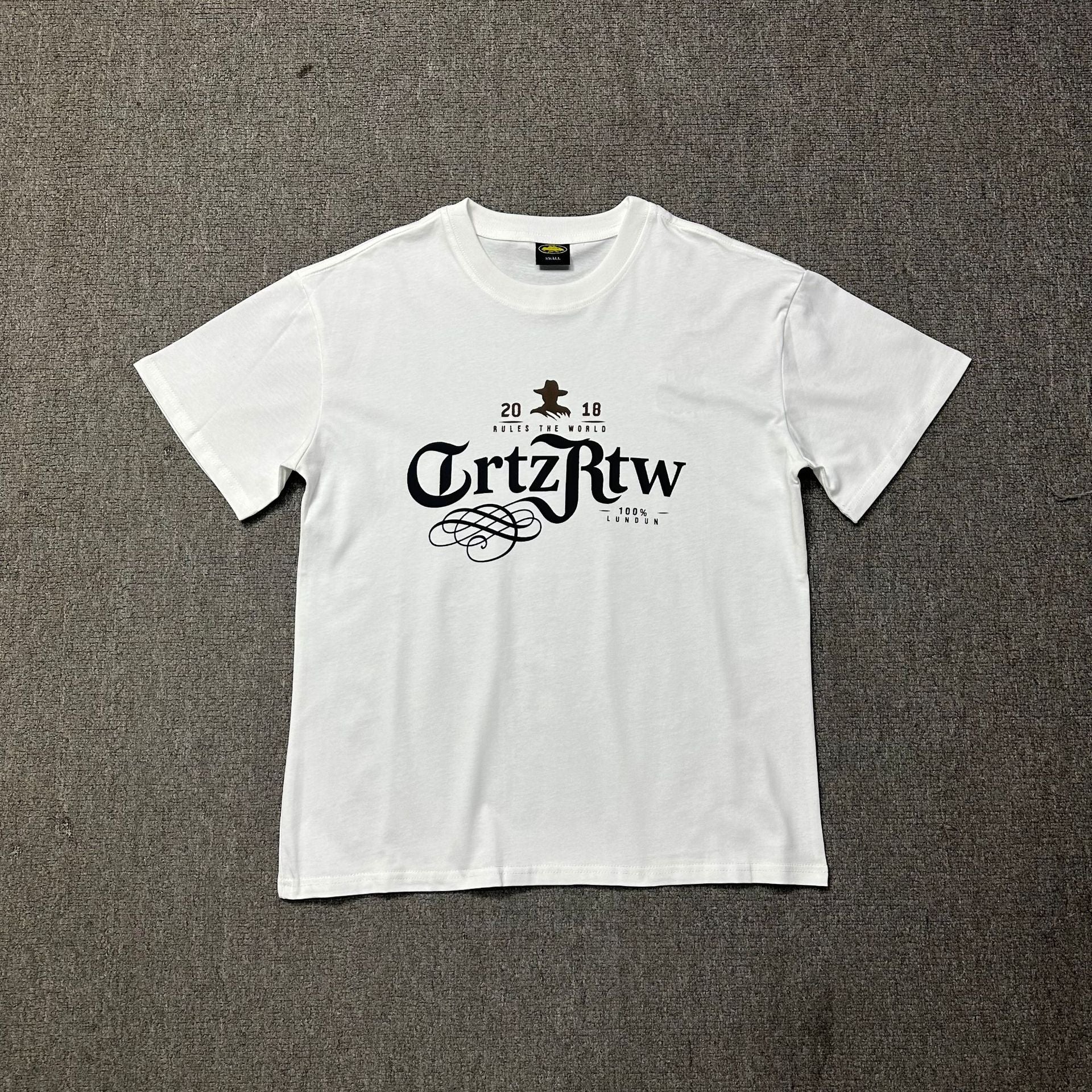 White t-shirt with black text and graphics on a gray surface