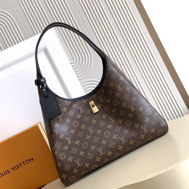 Louis Vuitton monogram shoulder bag in brown coated canvas with black leather trim and a gold-tone logo charm, shown on a light surface with a Louis Vuitton box partially visible.