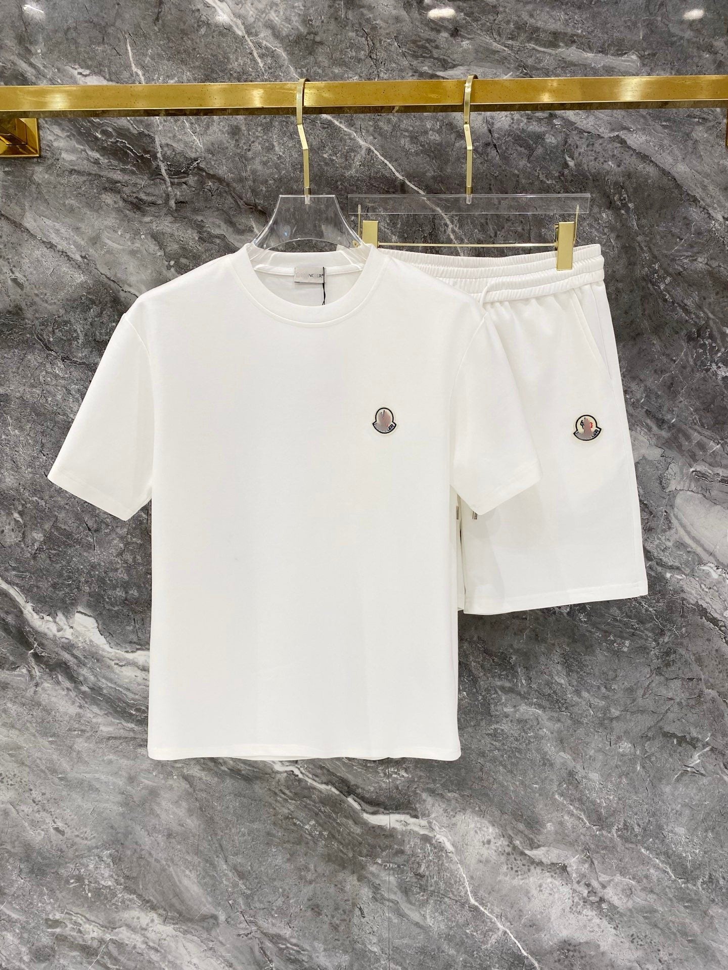 White t-shirt and shorts set on a hanger against a marble background