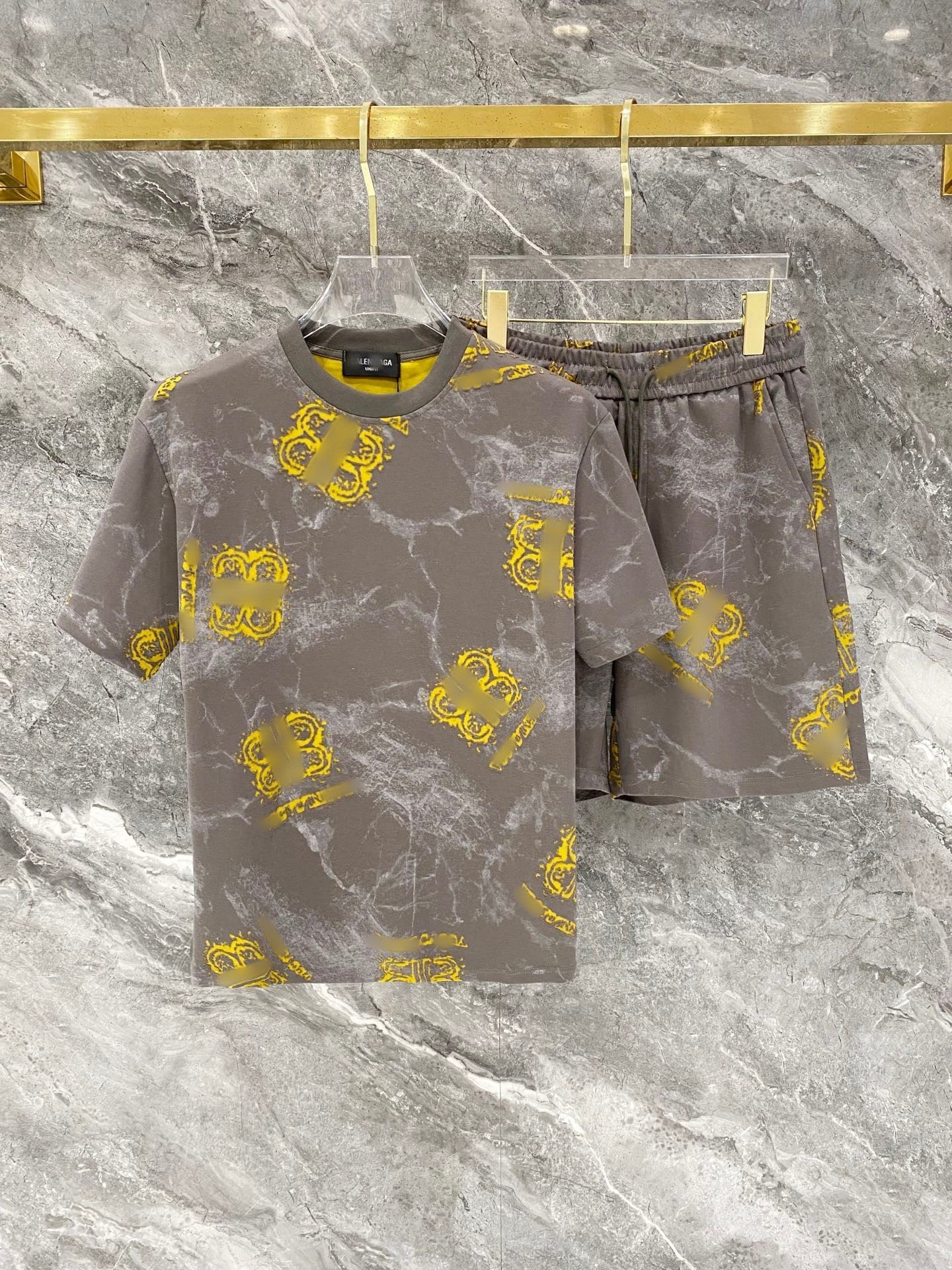 Gray t-shirt and shorts set with yellow patterns on a marble surface