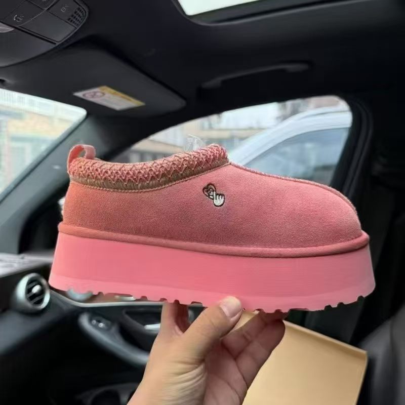 A pink slip-on platform sneaker with a knit collar and a small embroidered logo, held by a hand inside a car.