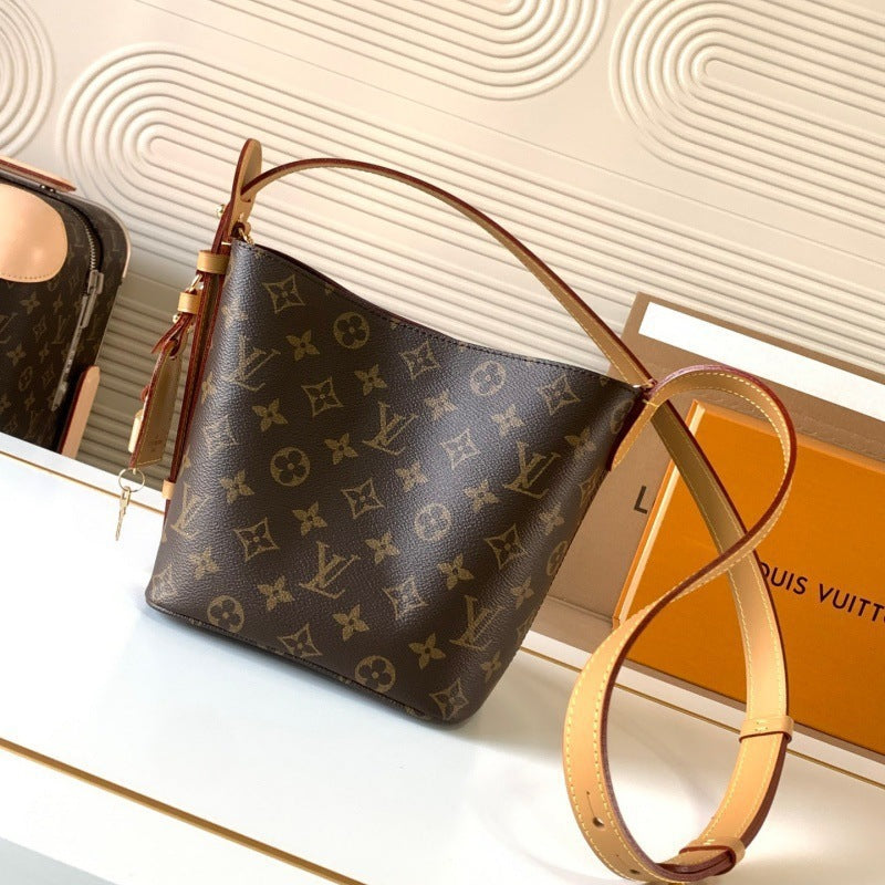 Louis Vuitton monogram canvas shoulder bag in dark brown with tan leather trim and strap, displayed on a white surface with a Louis Vuitton box in the background.