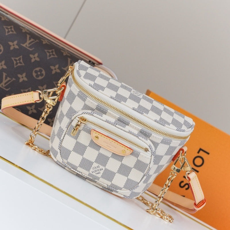 A Louis Vuitton mini crossbody bag in the Damier Azur checkered canvas, featuring a gold-tone chain strap and a beige leather logo tab, displayed on a white surface next to its orange and brown packaging.