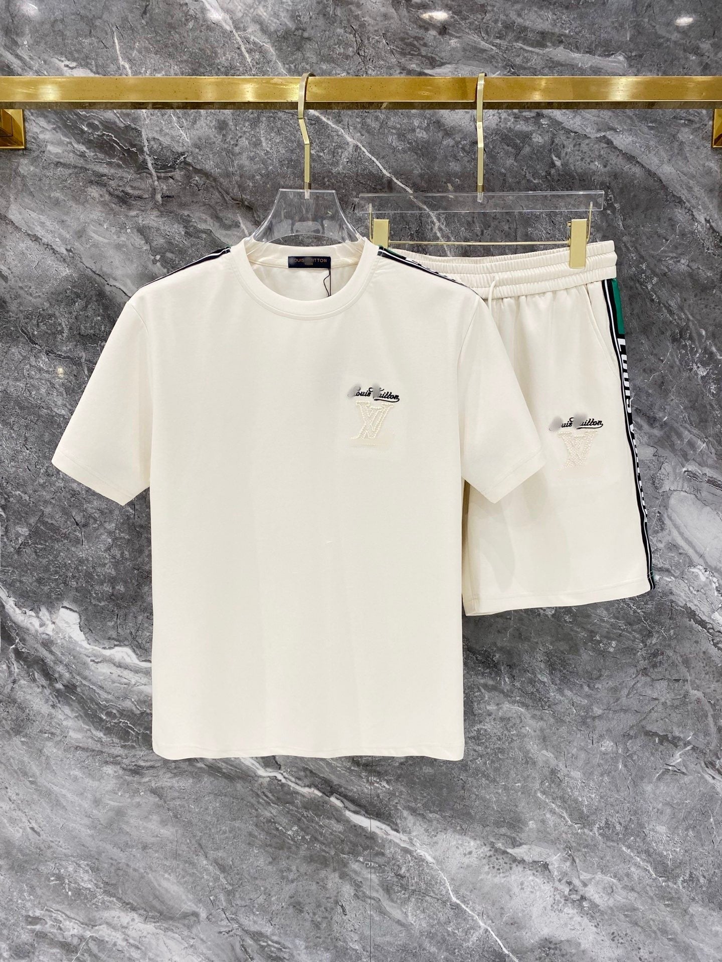 White t-shirt and shorts set on a hanger against a marble background