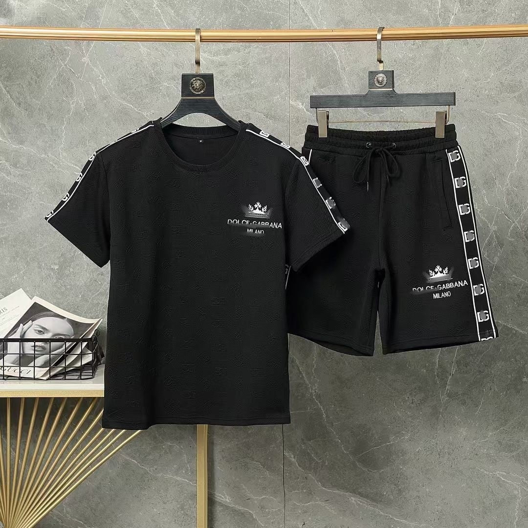 Black t-shirt and shorts set with brand logo on hangers against a gray background