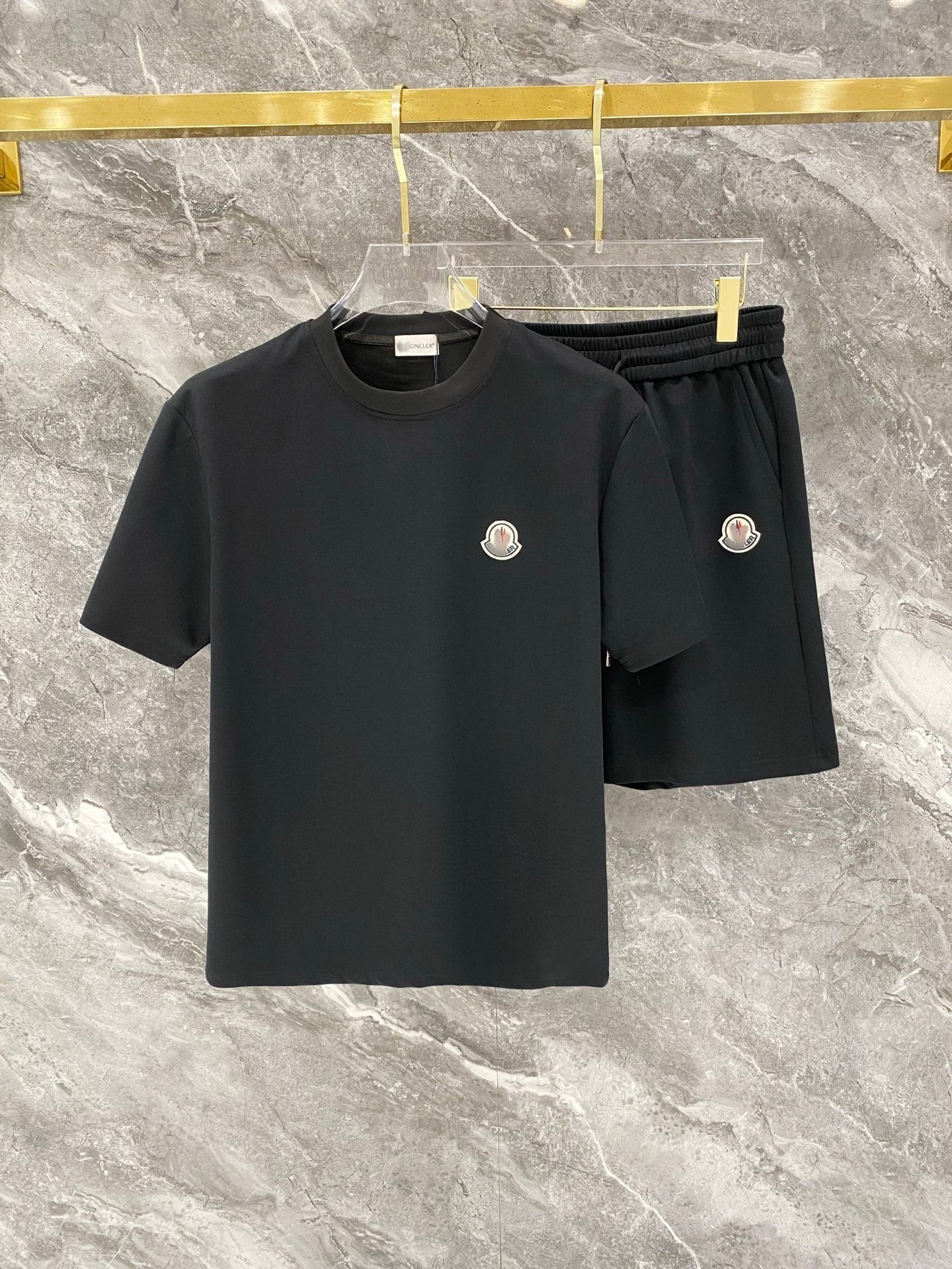 Black t-shirt and shorts set with brand logo on a marble surface