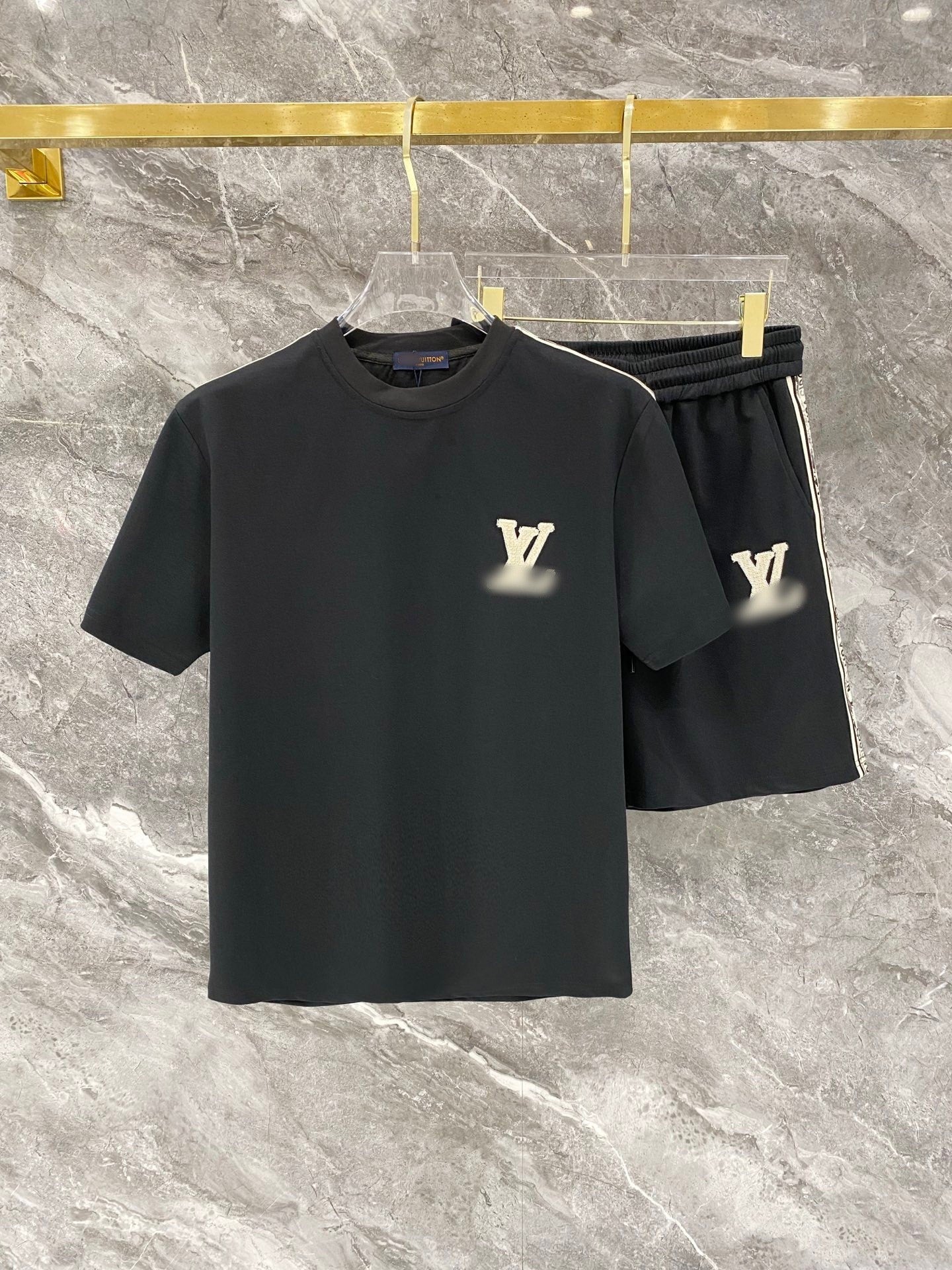 Black t-shirt and shorts set with brand logo on a marble surface