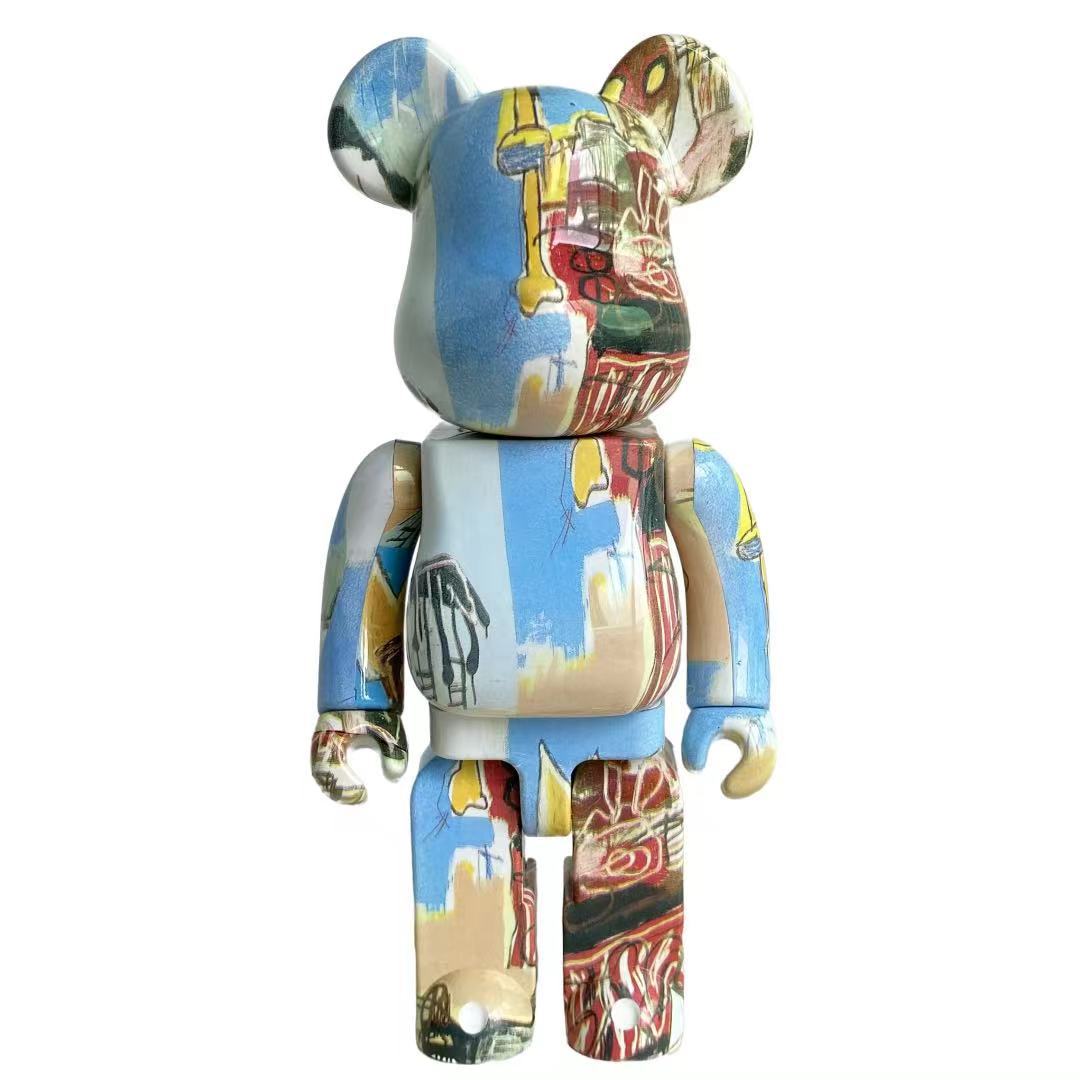 A bear-shaped collectible figure with a multicolor graffiti-style paint splatter pattern on a plain white background.