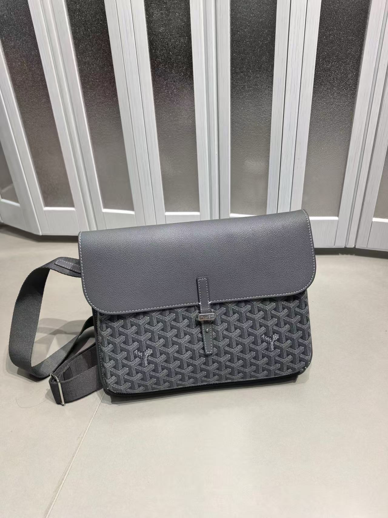 Gray patterned bag on a light-colored floor with a striped wall in the background