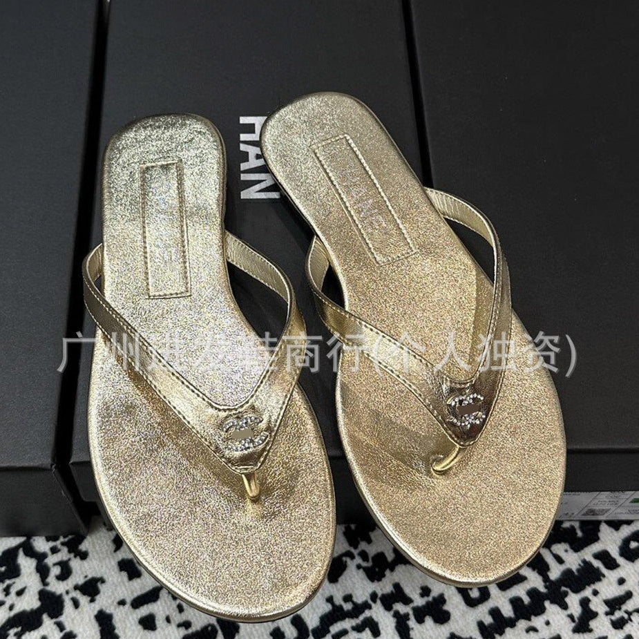 Pair of gold glittery flip-flops on a black surface with visible brand name.