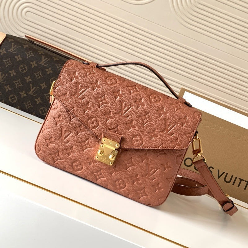 A Louis Vuitton monogram embossed leather shoulder bag in a dusty rose pink color, displayed on a white surface with a Louis Vuitton box in the background.