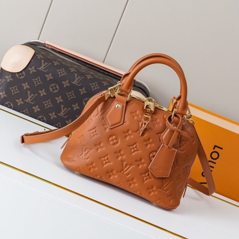 A Louis Vuitton monogrammed brown leather handbag with gold-tone hardware, displayed next to its orange Louis Vuitton box on a white surface.