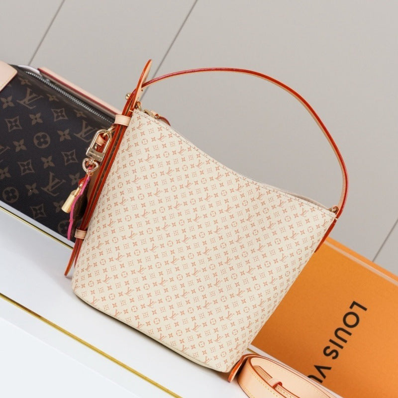Louis Vuitton monogram canvas shoulder bag in beige and orange-brown, displayed with a Louis Vuitton monogram pouch and an orange Louis Vuitton box on a light surface.