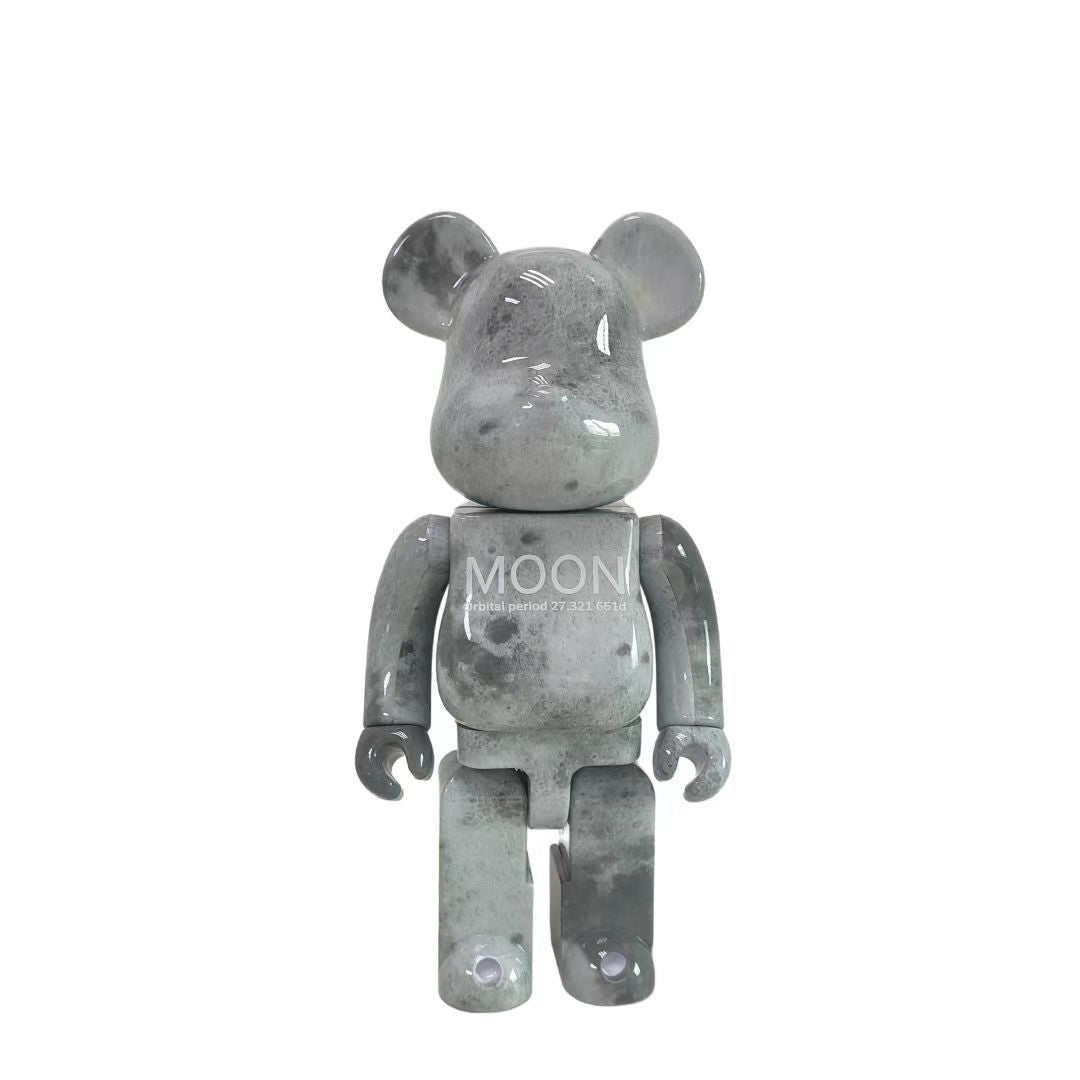 A Bearbrick-style collectible figure in a smoky translucent gray finish, centered on a plain white background. The chest has the word 'MOON' printed on it.