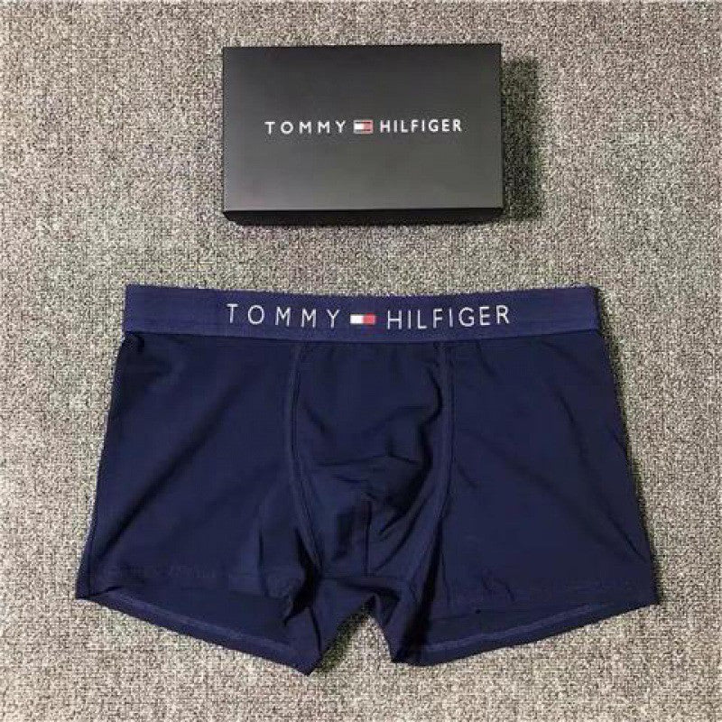 Tommy Hilfiger navy blue boxer briefs with logo waistband on a textured surface.