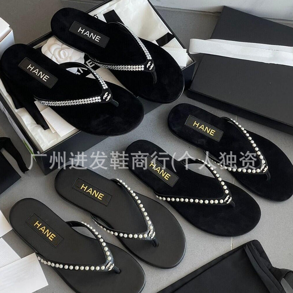 Black sandals with pearl details and 'HANE' branding on a gray surface.