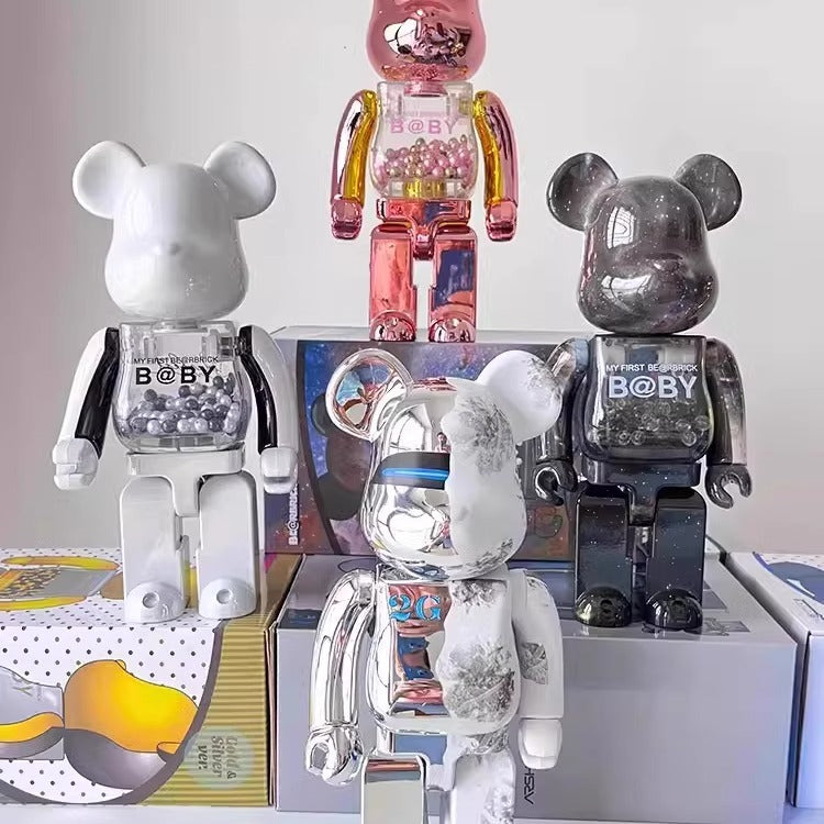 Four bear-shaped collectible figures arranged on display boxes against a plain light background. The figures have glossy finishes in white, translucent pink, metallic silver, and dark metallic gray, with 'BOBY' printed on the chest.