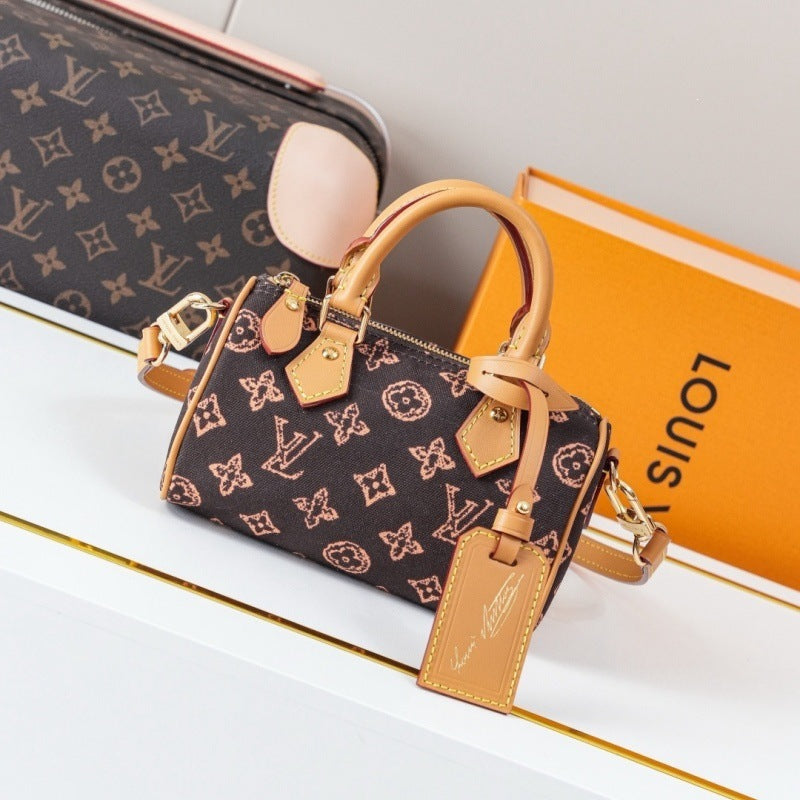 A Louis Vuitton monogram mini top-handle bag in dark brown coated canvas with tan leather trim and gold-tone hardware, displayed on a white surface with a matching orange Louis Vuitton box in the background.