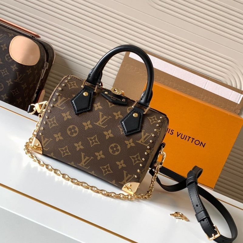 Louis Vuitton monogram canvas top-handle handbag with a gold chain strap, displayed on a white surface with an orange Louis Vuitton box in the background.