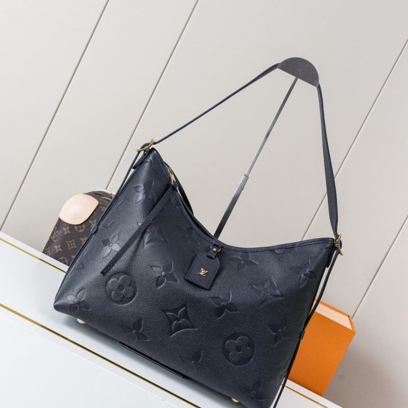 A Louis Vuitton shoulder bag in dark navy blue monogram coated canvas, displayed on a white surface with a Louis Vuitton box in the background.