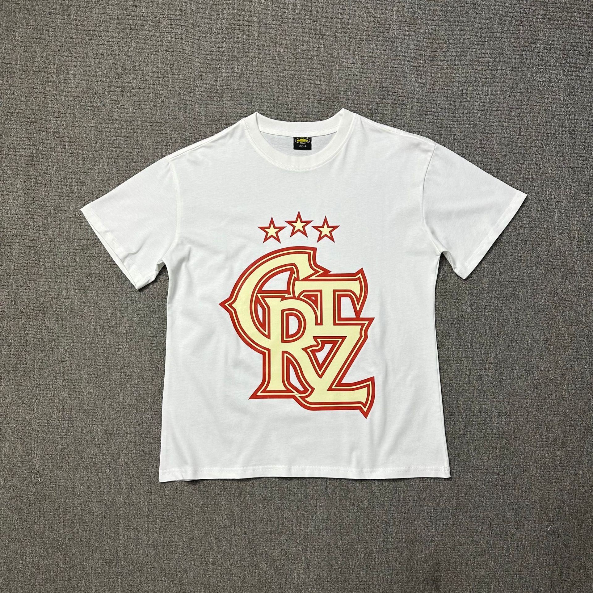 White t-shirt with red and yellow logo on a gray background