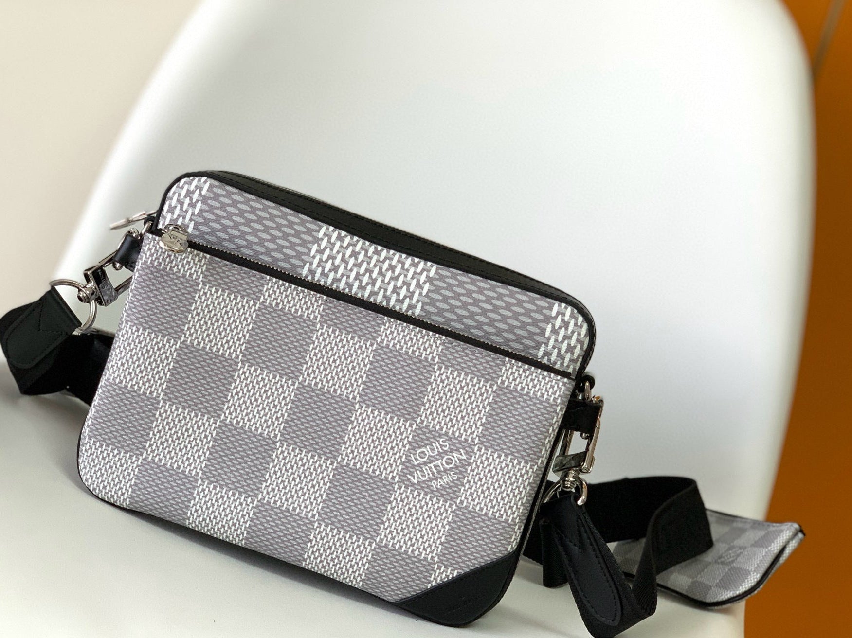 Gray checkered handbag with black accents on a white chair