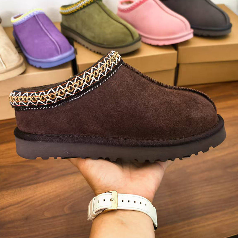 Brown indoor shoes on a hand with a wooden shelf in the background