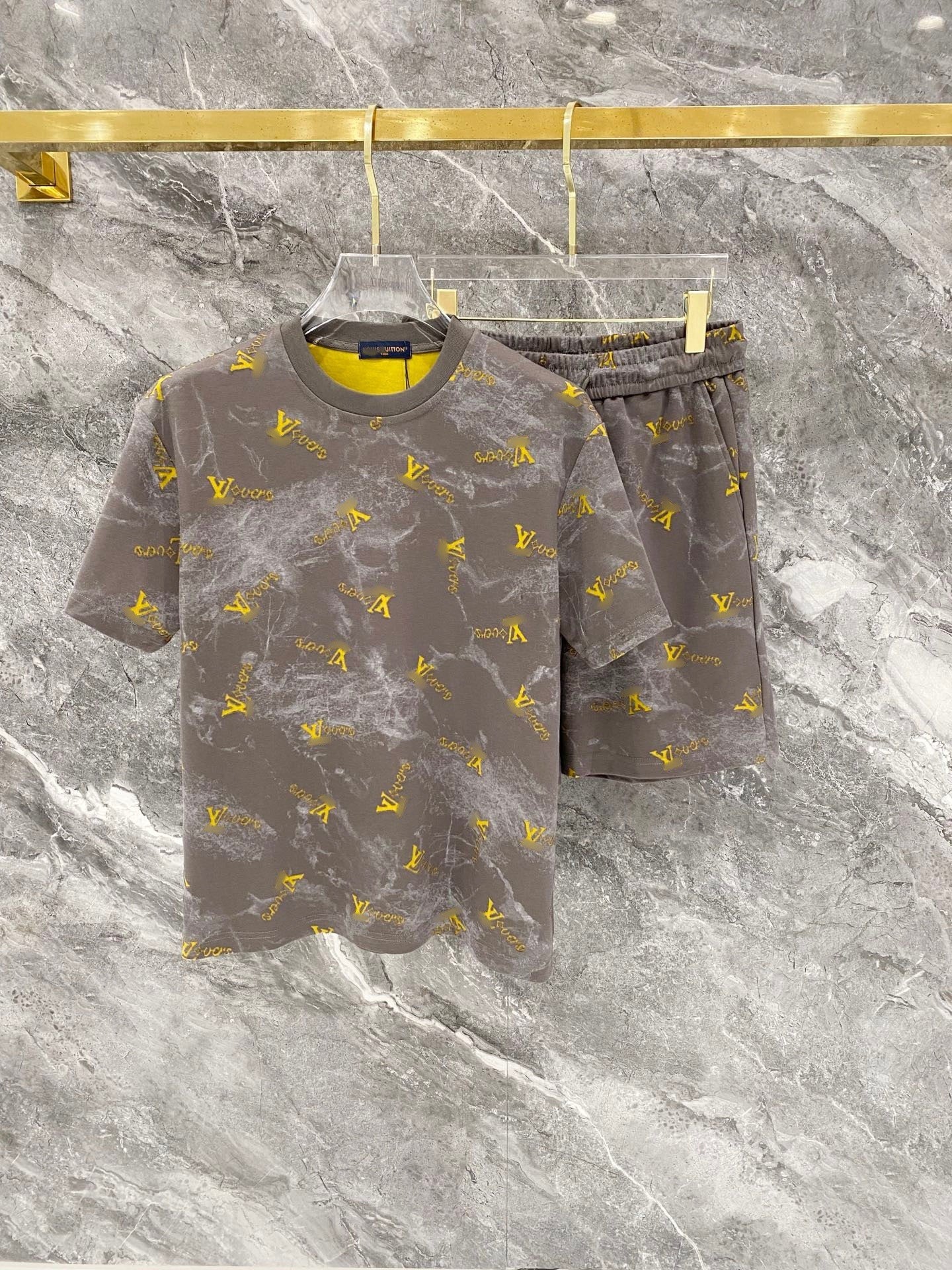 Gray t-shirt and shorts set with yellow patterns on a marble surface
