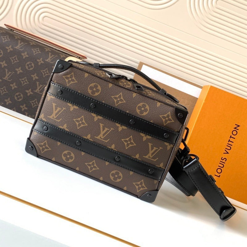 Louis Vuitton monogram canvas handbag with black leather trim and straps, displayed on a white surface next to an orange Louis Vuitton box.